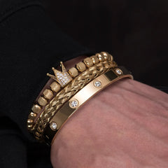 Close-up of a hand wearing multiple luxurious gold bracelets with intricate designs and embellishments.
